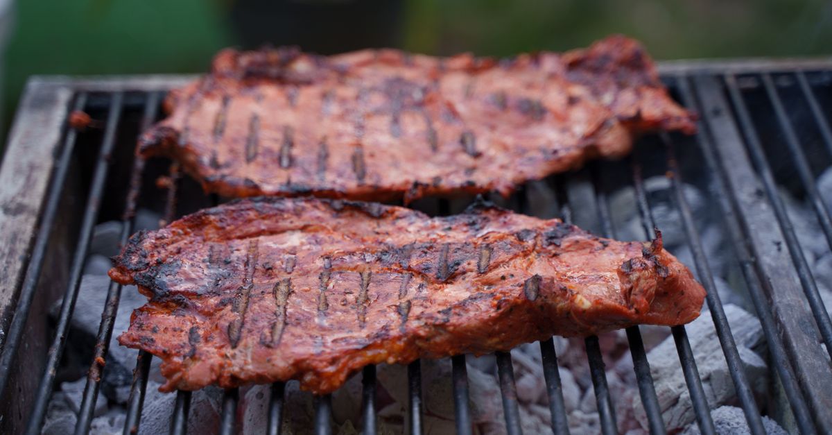 Bife de carne a la parrilla con marcas de brasa sobre una tabla de madera